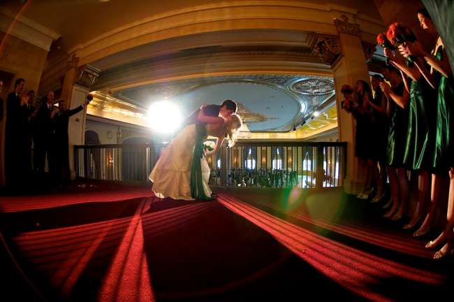 Wedding kis on balcony overlooking ballroom