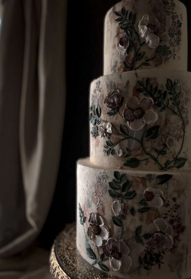 A 3-tier cake with painted florals and foliage, inspired by old-world, European influences and layered artistry.